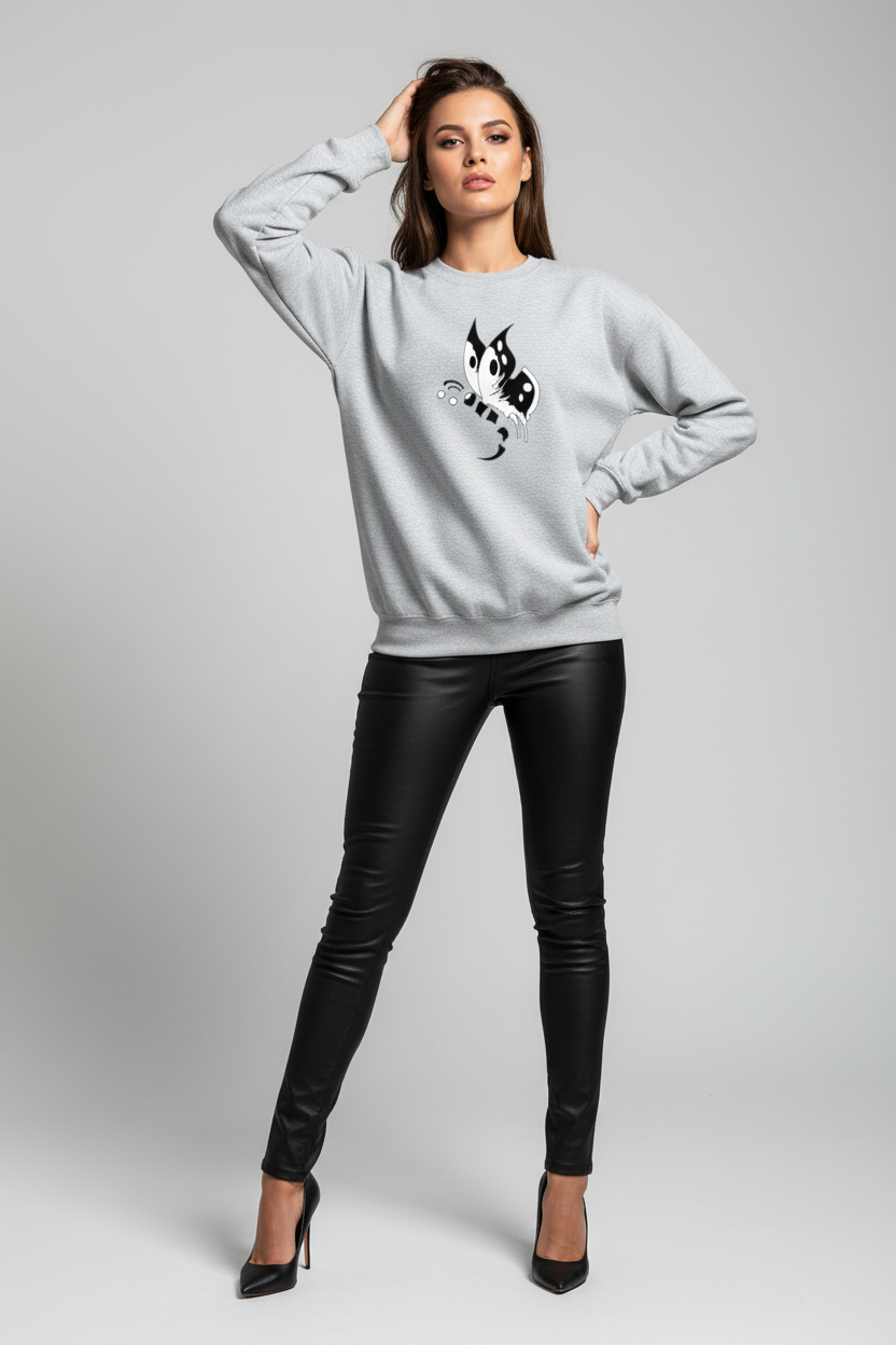 Woman wearing a light gray sweatshirt with a black and white design, paired with black leather pants on a gray background.
