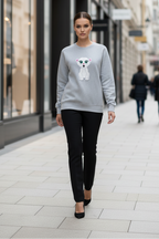 Woman wearing a gray sweater with a white dog design on a city street.