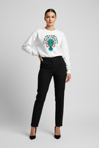 Woman wearing a white sweatshirt with a colorful design and black pants on a gray background