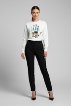 Woman wearing a white sweater with colorful design and black pants on a gray background