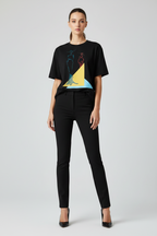Woman wearing a black t-shirt with a colorful design and black pants on a light gray background