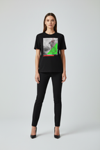 Woman wearing a black t-shirt with a graphic design on a plain background