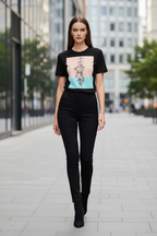 A woman walking down a city street wearing a black graphic t-shirt with a pastel color-block print and black skinny pants.
