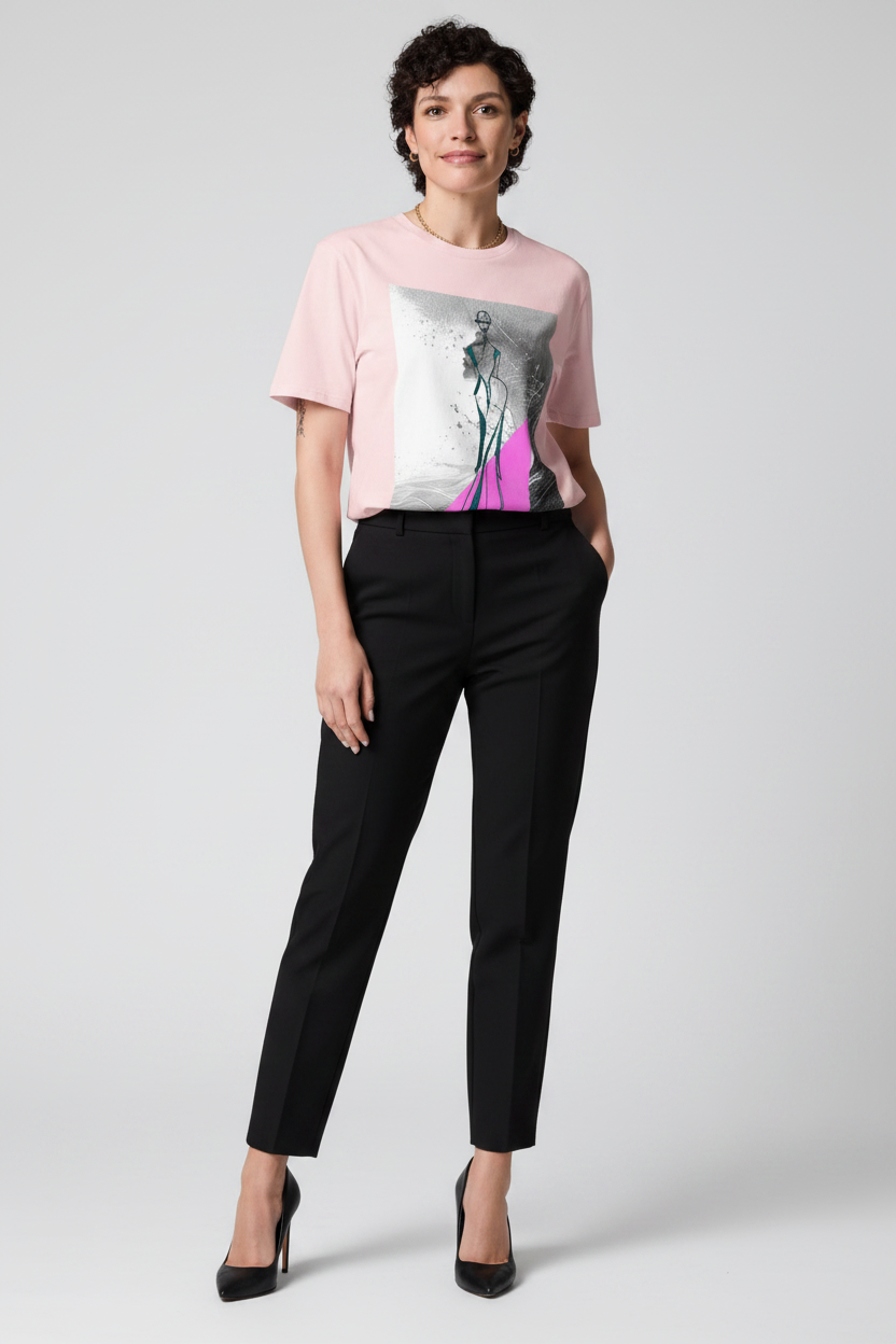 Woman wearing a pink t-shirt with a graphic design and black pants on a white background
