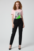 Woman wearing a pink t-shirt with a graphic design and black pants on a white background