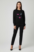 Woman wearing a black sweatshirt with a graphic design on a white background