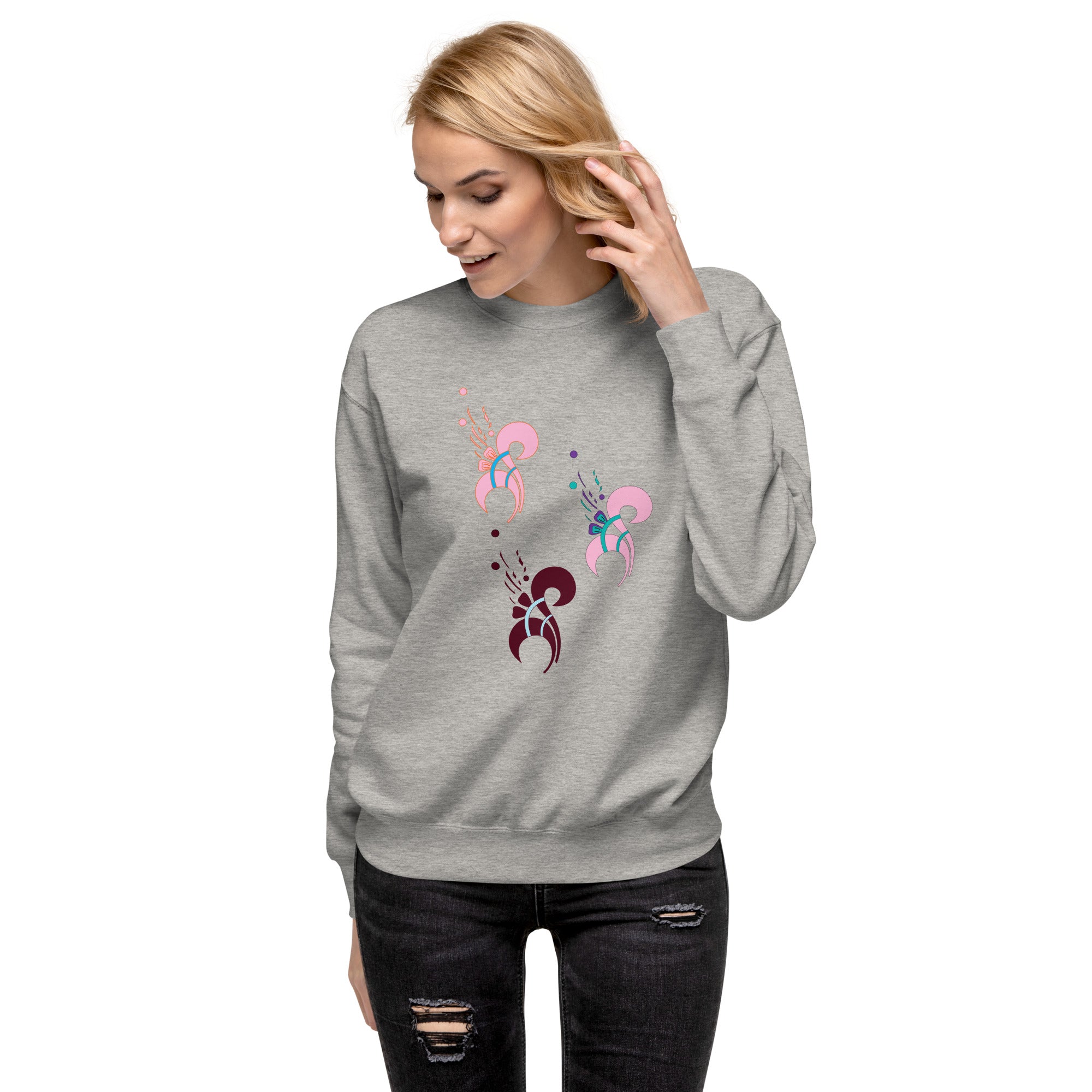 A woman wearing a charcoal gray sweatshirt with a floral print on the front, paired with ripped jeans.
