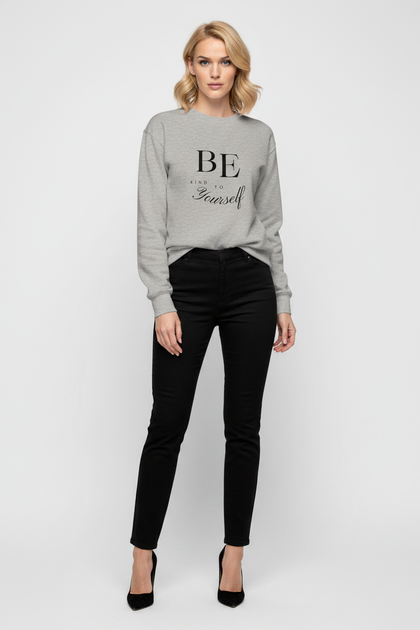 Woman wearing a gray sweatshirt with 'BE' text and black pants on a white background