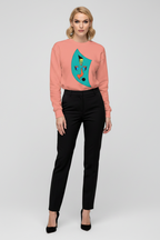Woman wearing a pink sweater with a colorful design and black pants on a white background