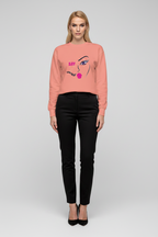 Woman wearing a pink sweatshirt with a graphic design on a plain background