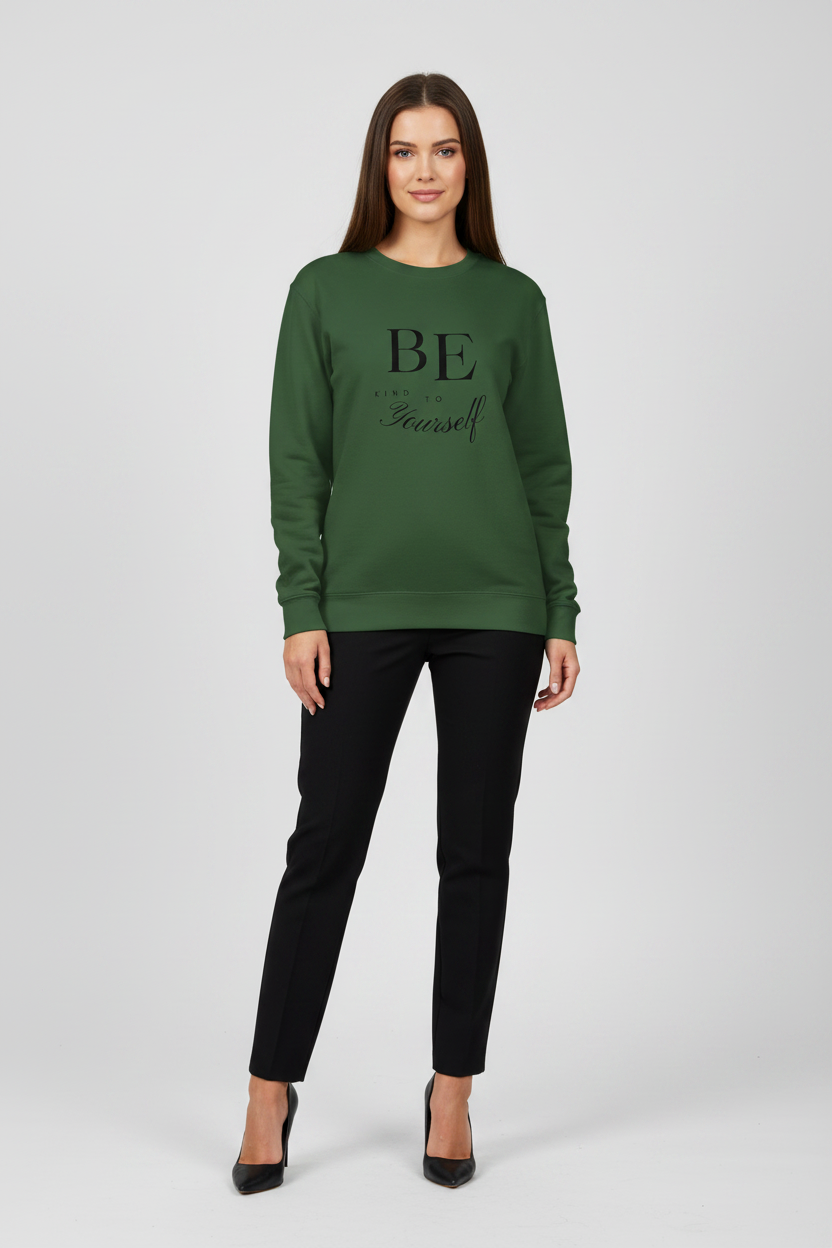 Woman wearing a green sweatshirt with 'BE' printed on it, standing against a white background