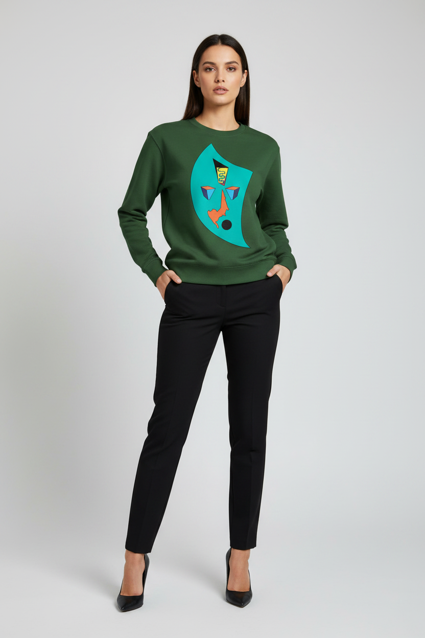 Woman wearing a green sweater with a colorful design and black pants on a white background