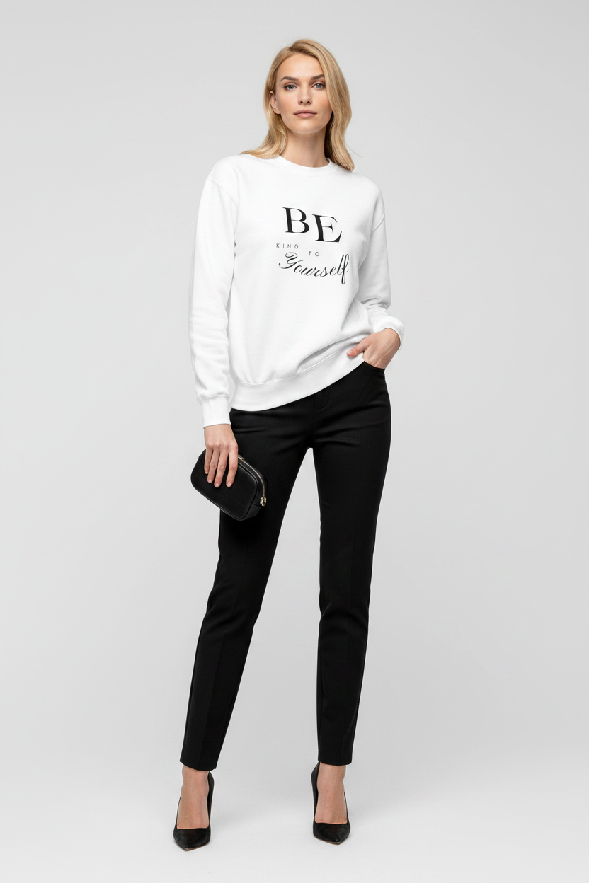 Woman wearing a white sweatshirt with text and black pants on a white background