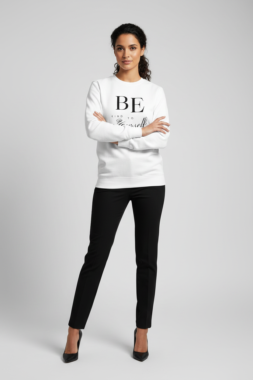 Woman wearing a white sweater with text and black pants on a gray background