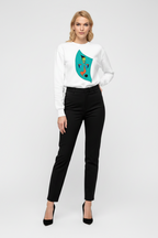 Woman wearing a white sweater with a colorful design and black pants on a white background