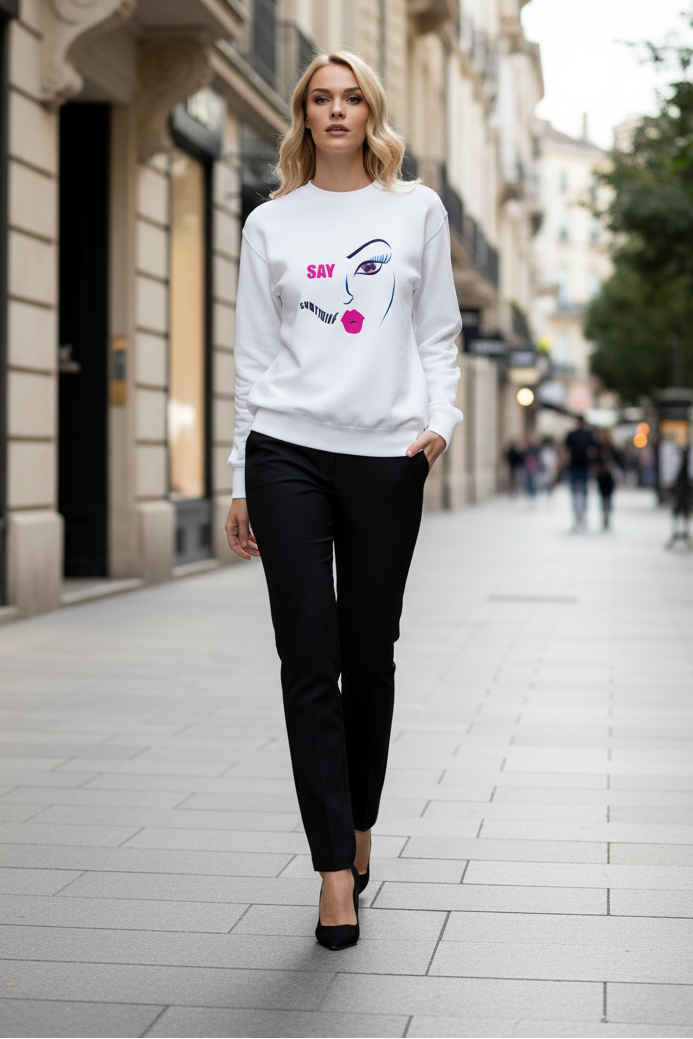 Woman wearing a white sweatshirt with a face design on a city street.
