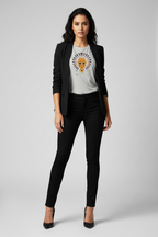 A woman modeling a black blazer, black skinny jeans, and a white graphic t-shirt with a lion print, standing against a light gray studio background.