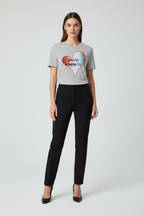 Woman wearing a gray t-shirt with a colorful heart design and black pants on a white background
