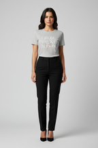 Woman wearing a gray t-shirt with text and black pants on a light gray background