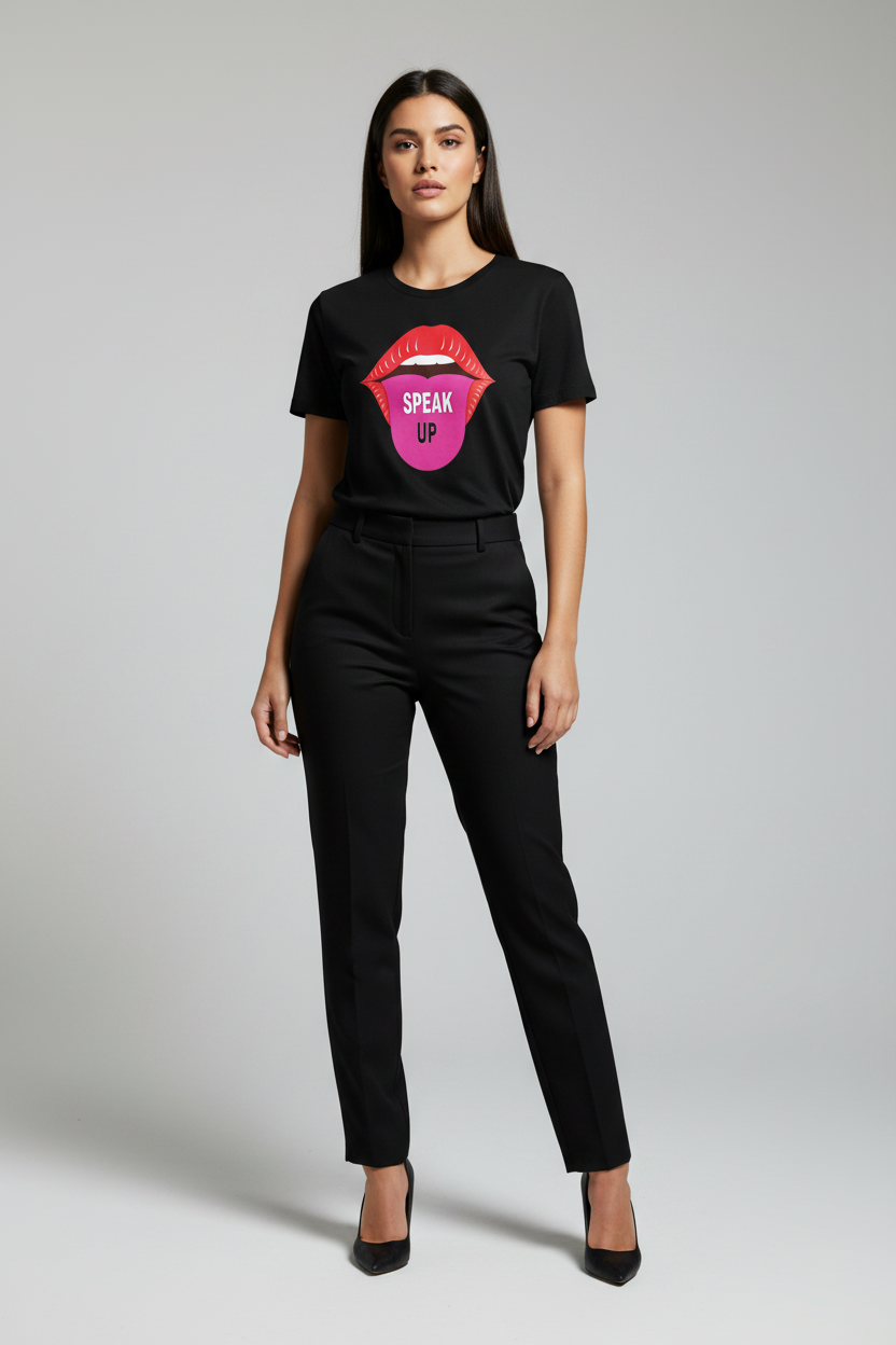 A woman modeling a black short-sleeve graphic T-shirt with a colorful lips design and the words 'SPEAK UP' in pink, paired with black trousers and black heels, against a light gray studio background.