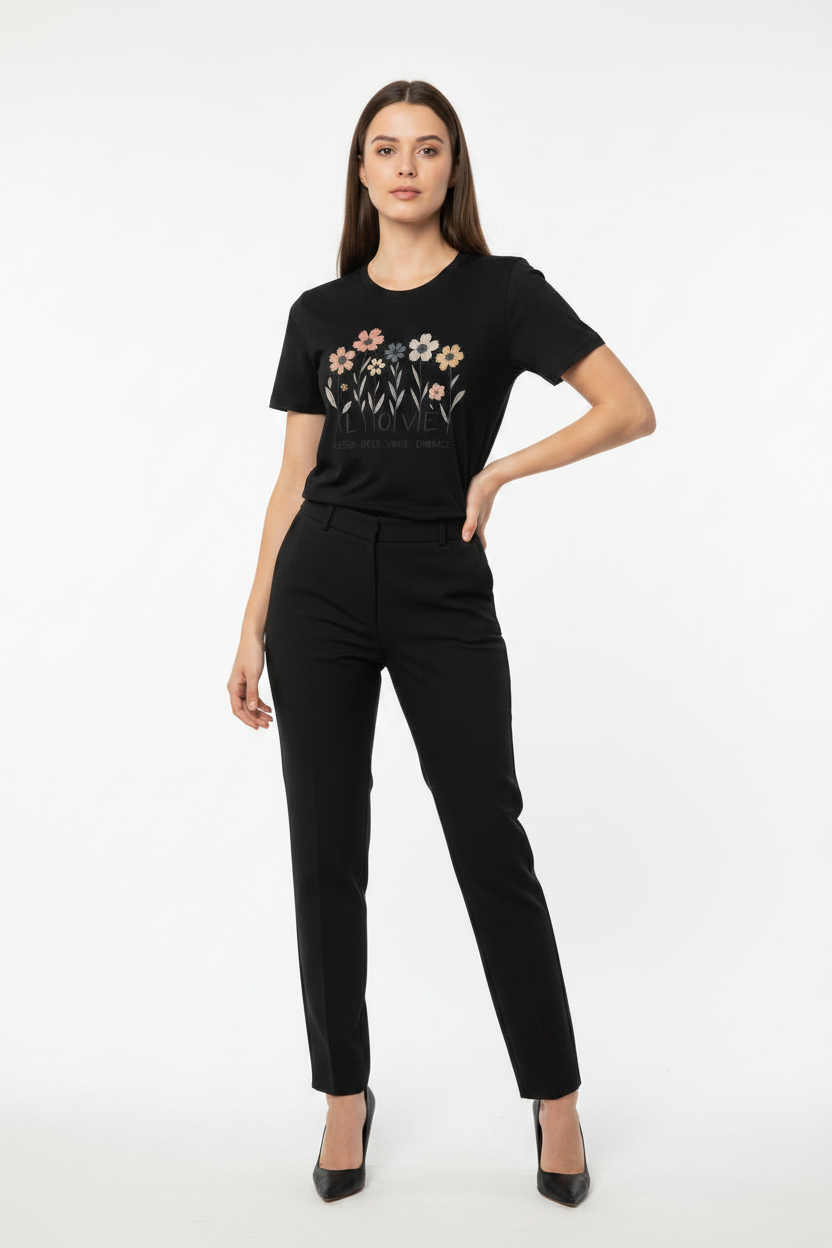 Woman wearing a black t-shirt with floral design and black pants on a white background
