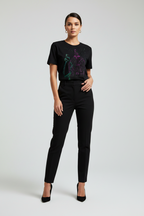 Woman wearing a black t-shirt with colorful design and black pants on a white background