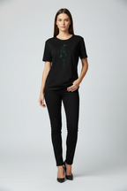 Woman wearing a black t-shirt with a green graphic and black pants on a white background