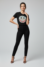 Woman wearing a black t-shirt with a smiley face design and black pants on a gray background