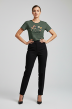 Woman wearing a green t-shirt with a floral design and text, standing against a plain background