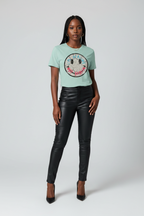 Woman wearing a light blue t-shirt with a graphic design and black leather pants on a white background