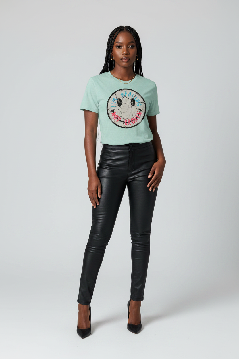 Woman wearing a light blue t-shirt with a graphic design and black leather pants on a white background