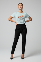 Woman wearing a light blue t-shirt with floral design and text, paired with black pants on a gray background