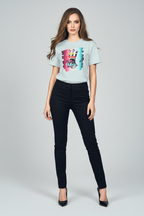 Woman wearing a light blue t-shirt with a colorful graphic and black pants on a gray background