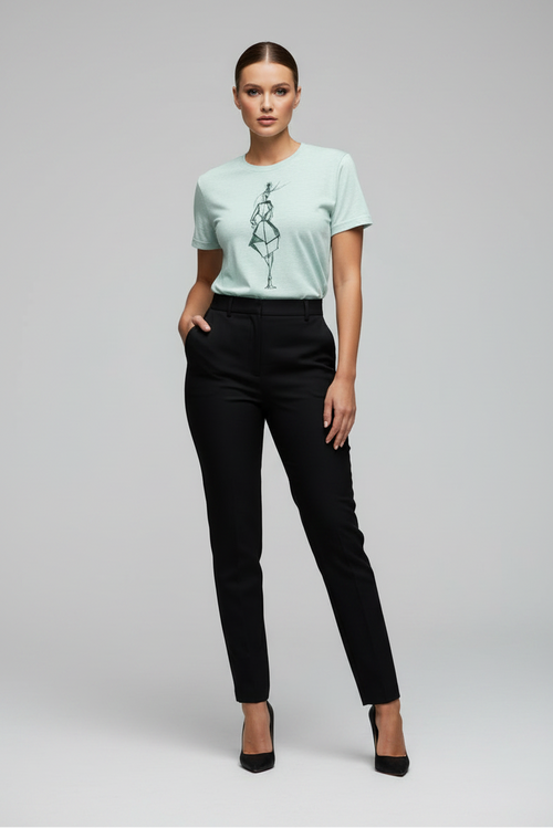 Woman wearing a light green t-shirt with a graphic design and black pants on a gray background