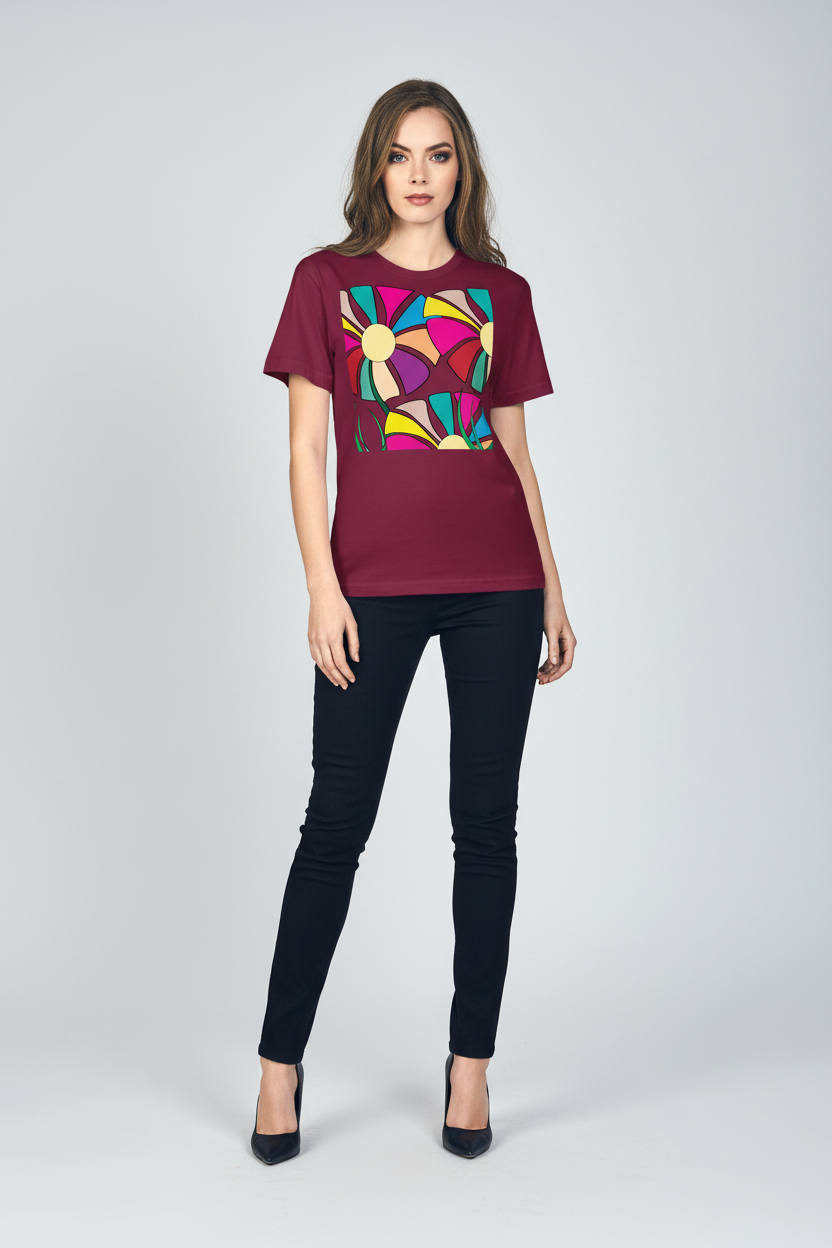 A woman modeling a short-sleeve crewneck t-shirt in deep burgundy with a colorful geometric graphic on the chest, paired with dark skinny jeans and black heels, against a light gray studio background.