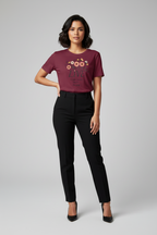 Woman wearing a maroon t-shirt with a graphic design and black pants on a gray background