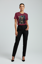 A woman modeling a short-sleeve crewneck t-shirt in burgundy with a colorful graphic print of a pug on the front, paired with black trousers and black heels, against a light gray studio background.