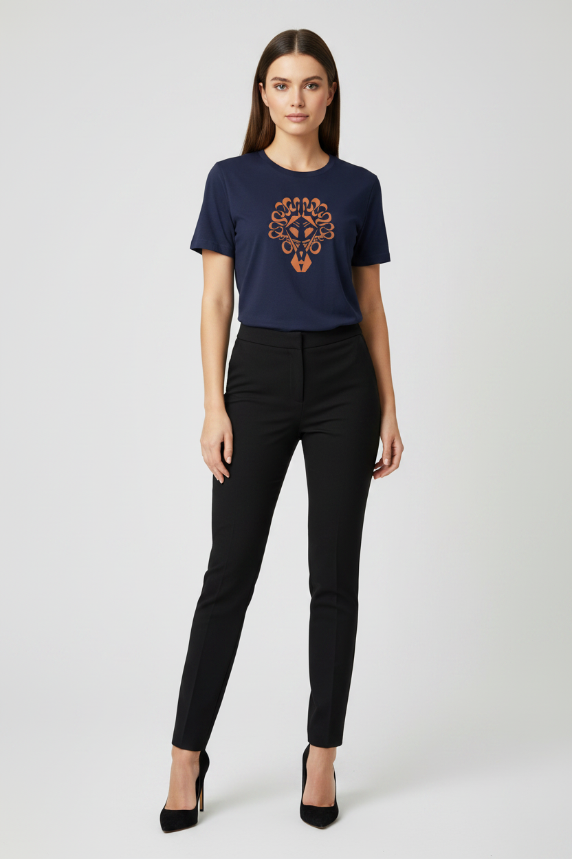 A woman modeling a navy blue short-sleeve t-shirt with a brown and orange graphic print on the chest, paired with black pants and black heels, against a light gray studio background.