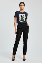 A model wearing a navy blue graphic t-shirt with a dog print and black trousers, standing against a light gray studio background.