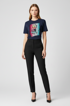 Woman wearing a navy t-shirt with a colorful graphic and black pants on a white background