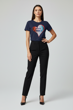 Woman wearing a navy blue t-shirt with a colorful heart design and black pants on a light gray background