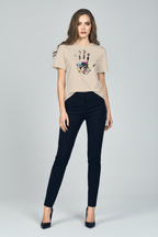 Woman wearing a beige t-shirt with a colorful design and black pants on a white background