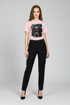 A woman modeling a light pink short-sleeve graphic t-shirt with a dog print, paired with black trousers and black heels, against a light gray studio background.