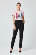 Woman wearing a pink graphic t-shirt and black pants on a white background
