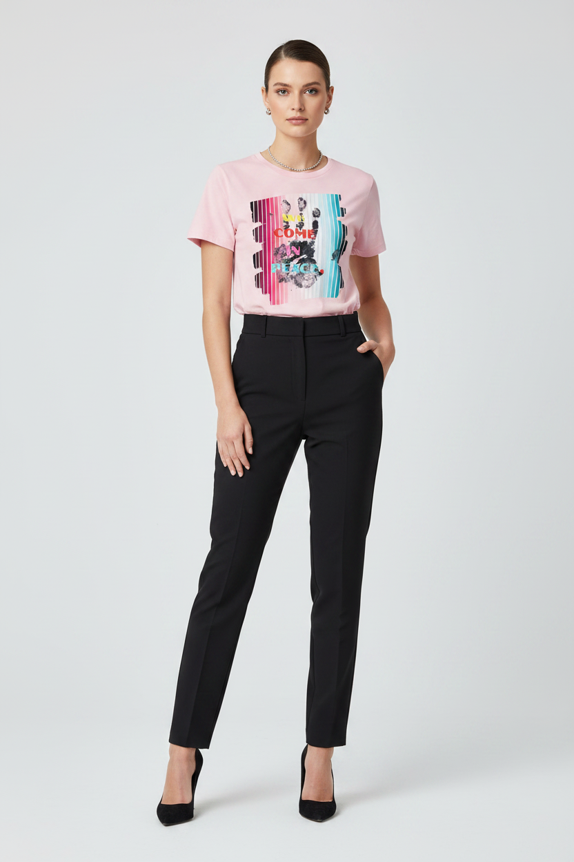 Woman wearing a pink graphic t-shirt and black pants on a white background