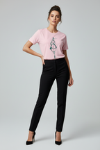 Woman wearing a pink t-shirt with a design and black pants on a gray background