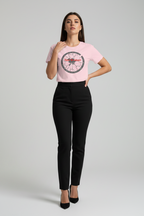 Woman wearing a pink t-shirt with a graphic design and black pants on a gray background