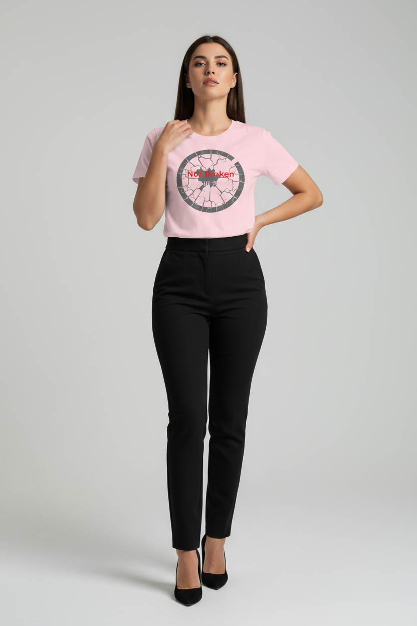 Woman wearing a pink t-shirt with a graphic design and black pants on a gray background