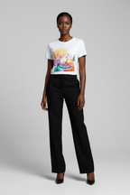 Woman wearing a white t-shirt with a colorful graphic and black pants on a gray background
