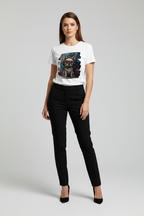 A woman modeling a white short-sleeve graphic T-shirt with a colorful dog print, paired with black pants and black heels, against a light gray studio background.